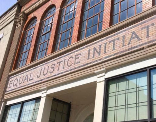 Large version of a brick building with large glass windows and the text 'Equal Justice Initiative above an entryway.